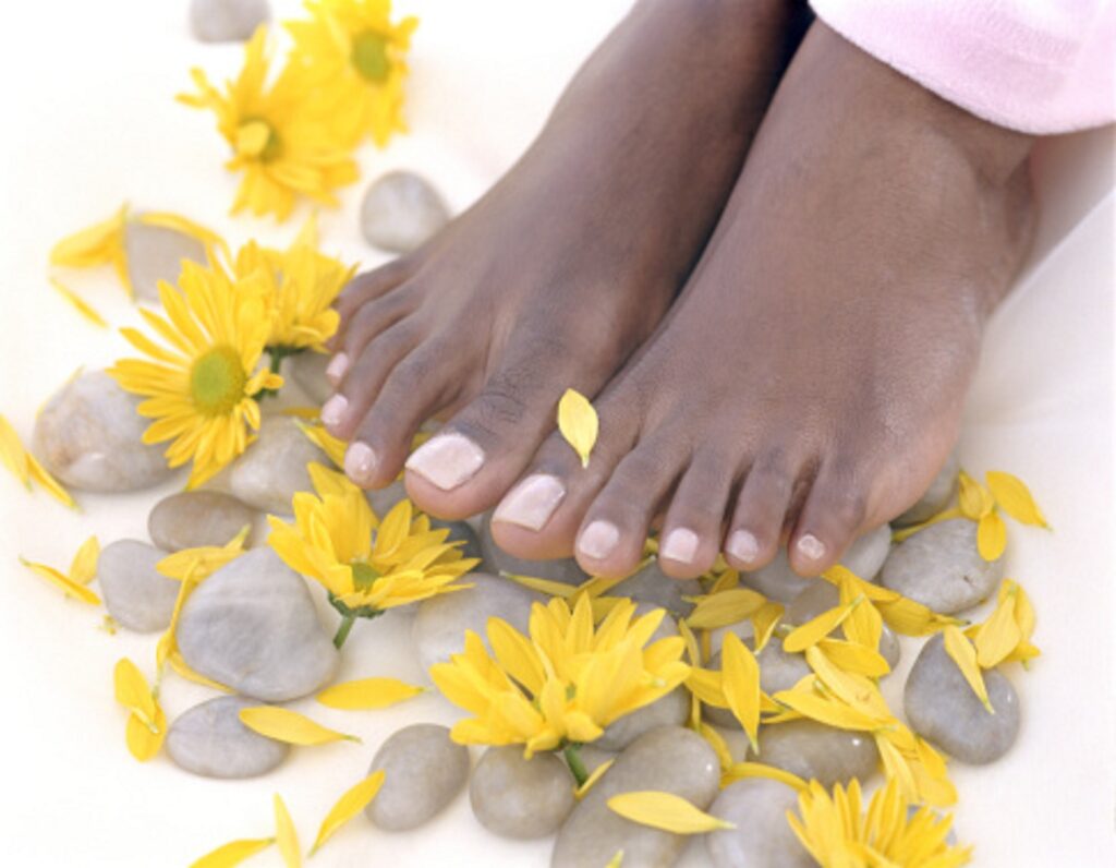 Woman's feet surrounded by pebbles and flower heads, close-up